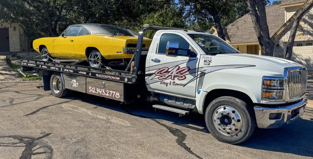 SAS Towing & Recovery flatbed tow truck transporting classic yellow Dodge Charger in Georgetown, TX – 24/7 towing service.