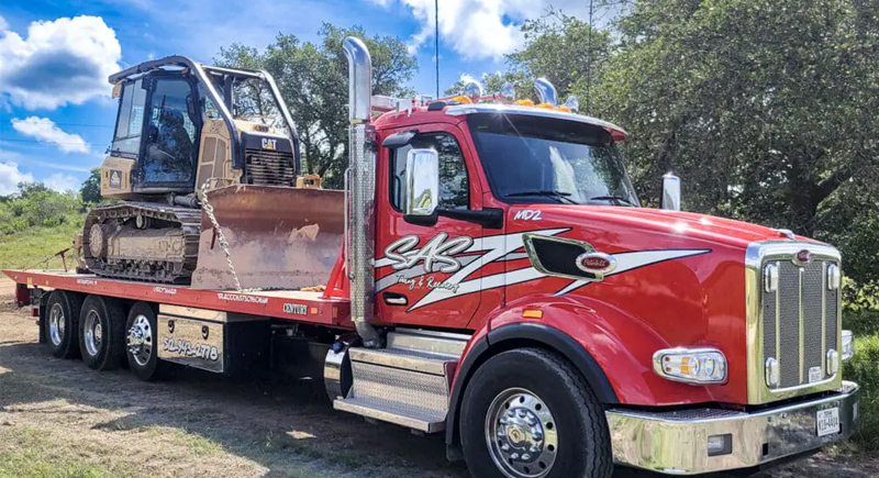 Flatbed tow truck transporting a tracked bulldozer for heavy equipment relocation